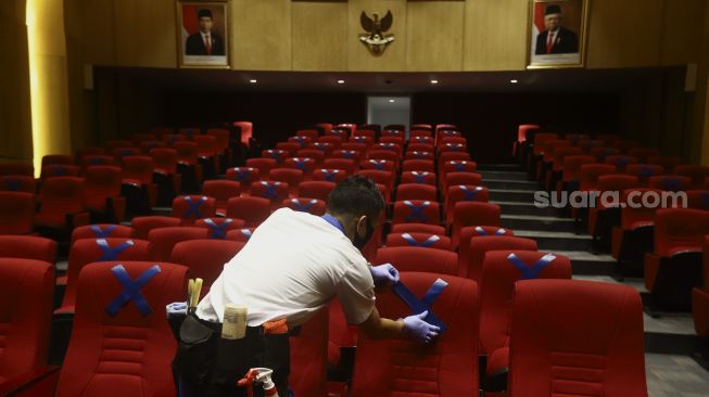 Petugas memasang tanda menjaga jarak fisik di ruang pemutaran film Perpustakaan Nasional Republik Indonesia, Jakarta, Rabu (10/6). [Suara.com/Angga Budhiyanto]