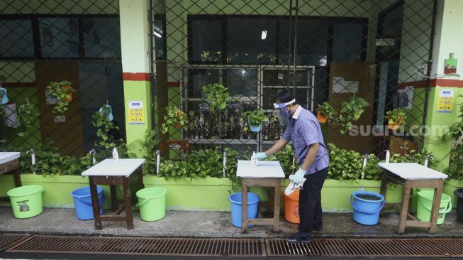 Petugas mempersiapkan tempat mencuci tangan bagi tamu di SMP Negeri 60, Kecamatan Gambir, Jakarta Pusat, Rabu (10/6). [Suara.com/Angga Budhiyanto]