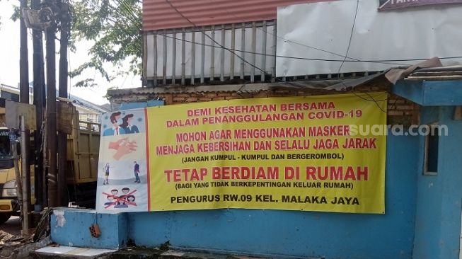 Spanduk imbauan di RW Zona Merah di Kelurahan Malaka Jaya, Duren Sawit, Jaktim. (Suara.com/Arga).