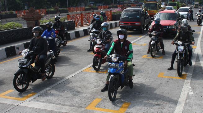 Pengendara motor berhenti di belakang garis untuk menjaga jarak antarpengendara di Karanglo, Malang, Jawa Timur, Kamis (11/6/2020). [ANTARA FOTO/Ari Bowo Sucipto]
