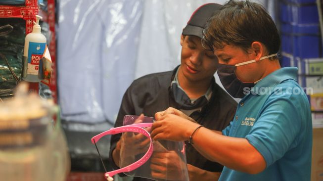 Pedagang merakit face shield untuk dijual di Pasar Pramuka, Jakarta Timur, kamis (11/6). [Suara.com/Alfian Winanto]
