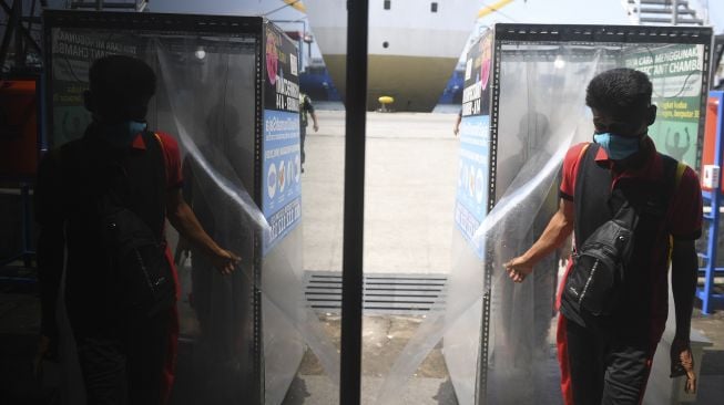 Seorang TKI Ilegal yang dipulangkan dari Malaysia keluar dari bilik disinfektan setibanya di Terminal Penumpang Nusantara Pelabuhan Tanjung Priok, Jakarta, Jumat (12/6/). [ANTARA FOTO/Akbar Nugroho Gumay]