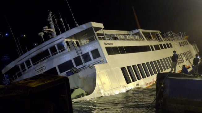 Warga mengamati KMP Dharma Rucitra III yang berada dalam posisi miring di Dermaga 2 Pelabuhan Padangbai, Karangasem, Bali, Sabtu (13/6) dini hari. [ANTARA FOTO/Fikri Yusuf]