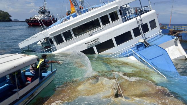 Petugas melakukan penanggulangan tumpahan minyak di sekitar area kandasnya KMP Dharma Rucitra III di Dermaga 2, Pelabuhan Padangbai, Karangasem, Bali, Sabtu (13/6/2020). [ ANTARA FOTO/Fikri Yusuf]
