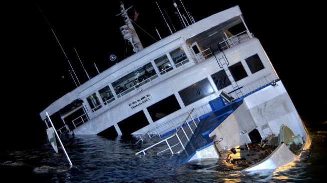 KMP Dharma Rucitra III berada dalam posisi miring dan hampir tenggelam di Dermaga 2 Pelabuhan Padangbai, Karangasem, Bali, Sabtu (13/6) dini hari. [ANTARA FOTO/Fikri Yusuf]