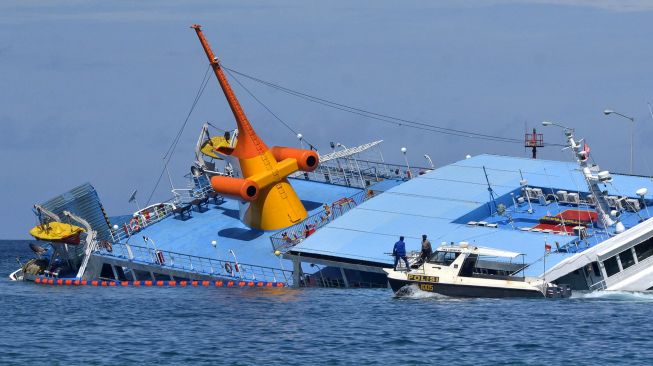 Petugas melintas di sekitar KMP Dharma Rucitra III yang kandas di Dermaga 2, Pelabuhan Padangbai, Karangasem, Bali, Sabtu (13/6/2020).  [ANTARA FOTO/Fikri Yusuf]