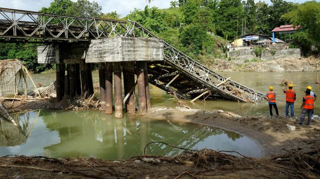 Sejumlah pekerja melihat kondisi jembatan Molintogupo yang ambruk diterjang banjir bandang di Alale, Kabupaten Bone Bolango, Gorontalo, Minggu (14/6/2020).  [ANTARA FOTO/Adiwinata Solihin]