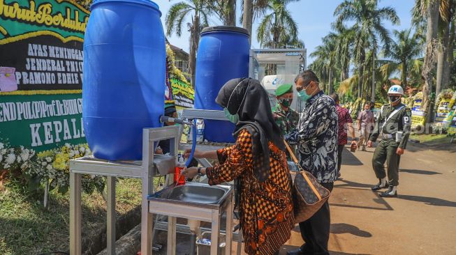 Pelayat mencuci tangan sebelum melayat kerumah duka mantan Kepala Staf TNI Angkatan Darat (KSAD) Letjen TNI Pramono Edhie Wibowo di Puri Cikeas, Bogor, Jawa Barat, Minggu (14/6). [Suara.com/Alfian Winanto]