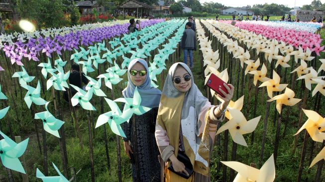 Pengunjung berswafoto di kebun kincir angin "Rainbow Garden" di Kelurahan Tamarunang, Gowa, Sulawesi Selatan, Minggu (14/6/2020).  [ANTARA FOTO/Arnas Padda]