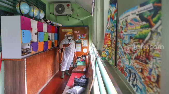 Petugas PMI menyemprotkan cairan disinfektan di lorong-lorong kelas SDN 01 Menteng, Jakarta Pusat, Senin (15/1). [Suara.com/Alfian Winanto]