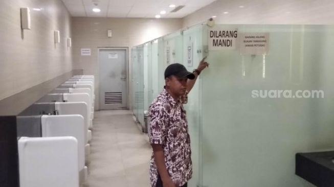 Penjaga Toilet bawah tanah, Yoyok (45) menunjukkan larangan mandi di dalam WC pria, Senin (15/6/2020). [Suarajogja.id / Baktora]