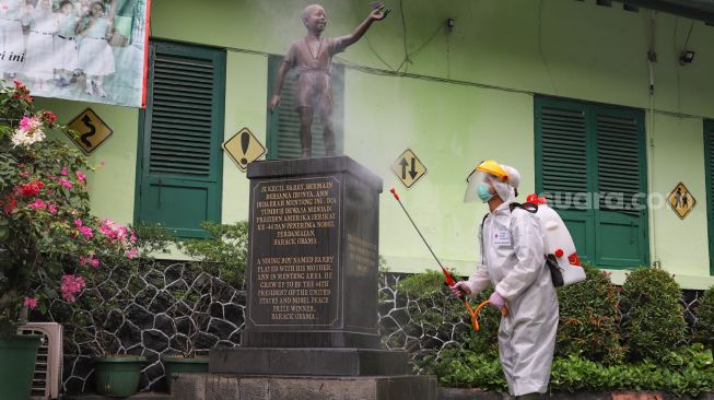 Petugas PMI menyemprotkan cairan disinfektan ke patung Barrack Obama di SDN 01 Menteng, Jakarta Pusat, Senin (15/1). [Suara.com/Alfian Winanto]