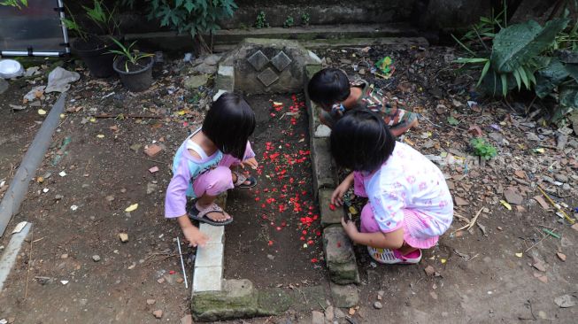 Anak - anak bermain di kuburan di Pisangan, Jakarta Timur, Selasa (16/5). [Suara.com/Alfian Winanto]