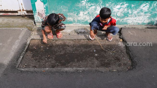 Anak - anak bermain di kuburan di Pisangan, Jakarta Timur, Selasa (16/5). [Suara.com/Alfian Winanto]