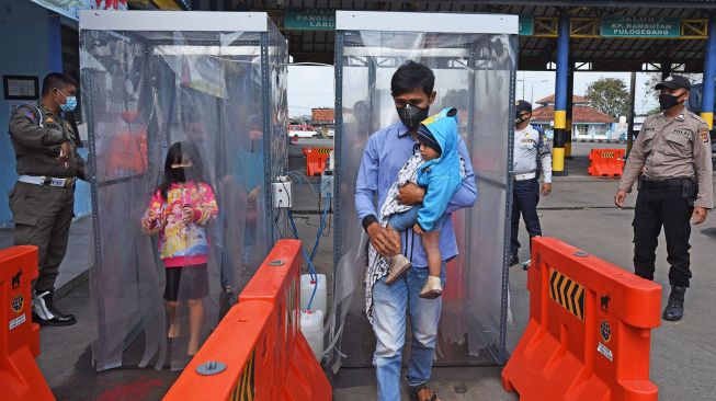 Calon penumpang melewati bilik penyemprot disinfektan di Terminal Bus AKAP Pakupatan, Serang, Banten, Rabu (17/6/2020).  [ANTARA FOTO/Asep Fathulrahman]