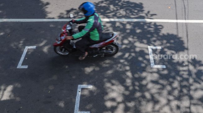 Pengendara motor berhenti pada garis pembatas antar pengendara di Jalan Hang Tuah Raya, Jakarta Selatan, Selasa, (16/6). [Suara.com/Alfian Winanto]