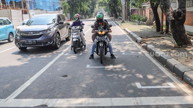 Pengendara motor berhenti pada garis pembatas antar pengendara di Jalan Hang Tuah Raya, Jakarta Selatan, Selasa, (16/6). [Suara.com/Alfian Winanto]