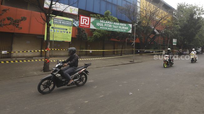 Sejumlah kendaraan melintas di Pasar Kebayoran Lama yang ditutup di Jakarta, Kamis (18/6). [Suara.com/Angga Budhiyanto]