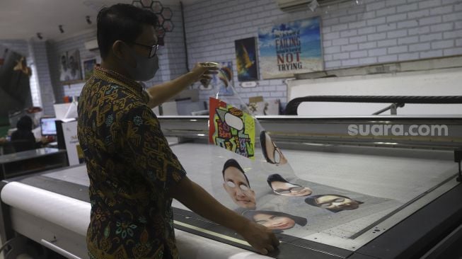 Pekerja menggunakan pelindung wajah berkarakter di percetakan Bintang Sempurna, Bendungan Hilir, Jakarta Pusat, Jumat (19/6). [Suara.com/Angga Budhiyanto] 