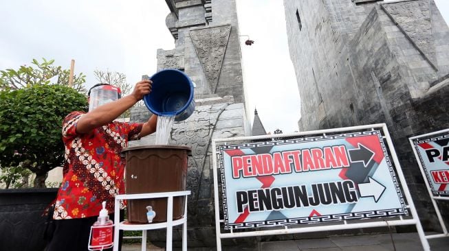 Petugas Dinas Pariwisata mengisi air ke wadah tempat cuci tangan yang dipersiapkan di kawasan pusara Makam Presiden Soekarno di Blitar, Jawa Timur, Jumat (19/6/2020).  [ANTARA FOTO/Irfan Anshori]