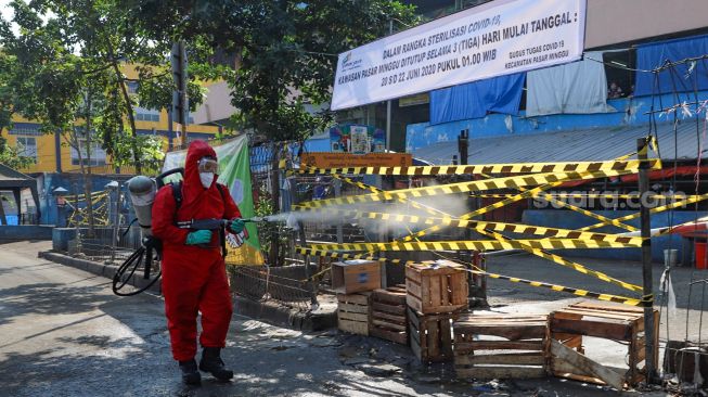 Petugas menyemprotkan cairan disinfektan di area Pasar Minggu, Jakarta Selatan, Sabtu (20/6). [Suara.com/Alfian Winanto]