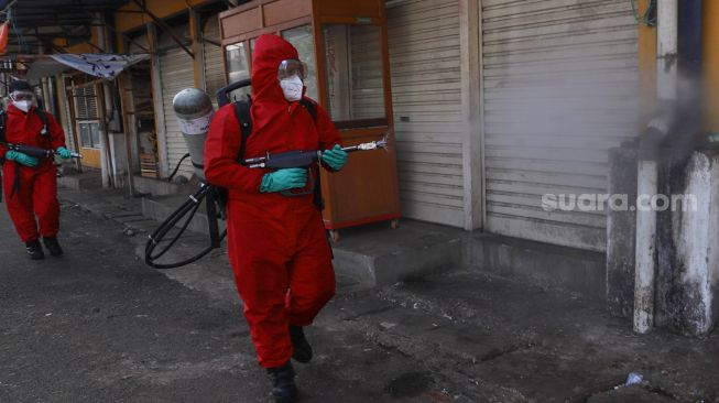 Petugas menyemprotkan disinfektan di area Pasar Minggu, Jakarta Selatan, Sabtu (20/6). [Suara.com/Alfian Winanto]