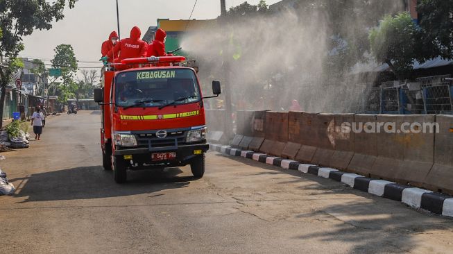 Petugas menyemprotkan disinfektan dengan truk Damkar di area Pasar Minggu, Jakarta Selatan, Sabtu (20/6). [Suara.com/Alfian Winanto]
