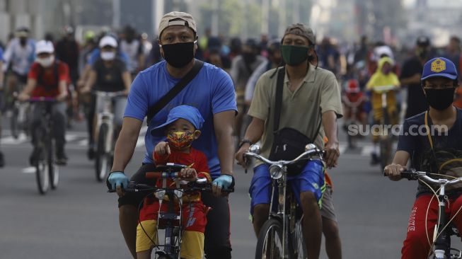 Sejumlah warga berolahraga menggunakan sepeda di Jalan M.H Thamrin, Jakarta, Minggu (21/6). [Suara.com/Angga Budhiyanto]