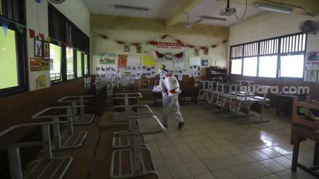 Petugas Palang Merah Indonesia (PMI) Jakarta Pusat menyemprotkan cairan disinfektan di lingkungan Sekolah Menengah Kejuruan Negeri (SMKN) 19, Bendungan Hilir Jakarta Pusat, Senin (22/6). [Suara.com/Angga Budhiyanto]    