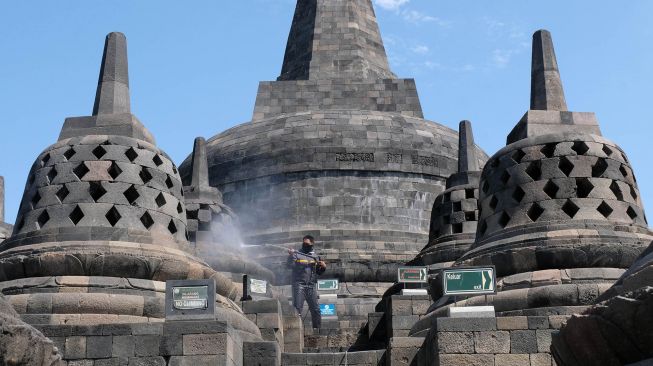 Petugas Balai Konservasi Borobudur (BKB) menyemprotkan air saat membersihkan abu vulkanik erupsi gunung Merapi di Candi Borobudur, Magelang, Jawa Tengah, Senin(22/6/2020).  [ANTARA FOTO/Anis Efizudin]