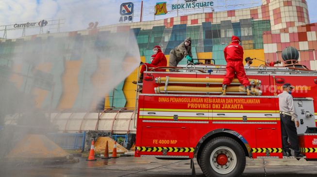 Petugas melakukan penyemprotan disinfektan di area Terminal Blok M, Jakarta Selatan, Selasa (23/6).  [Suara.com/Alfian Winanto]