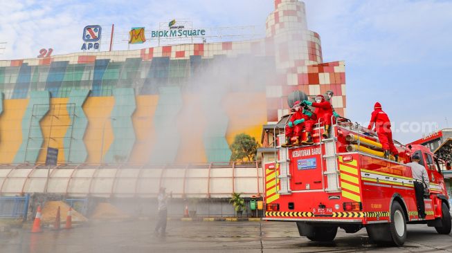 Petugas melakukan penyemprotan disinfektan di area Terminal Blok M, Jakarta Selatan, Selasa (23/6).  [Suara.com/Alfian Winanto]