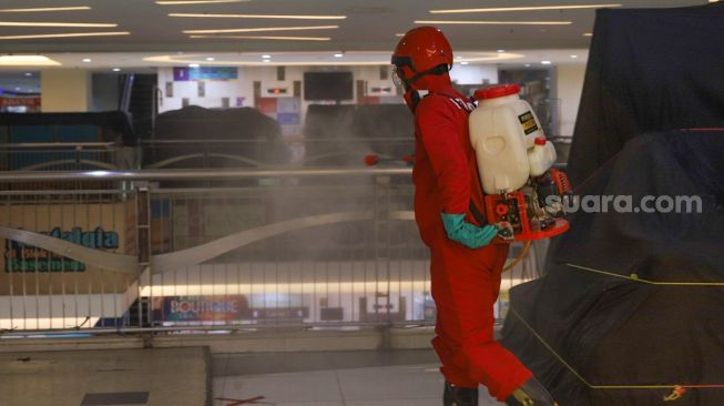 Petugas menyemprot disinfektan di Blok M Square, Jakarta Selatan, Selasa (23/6). [Suara.com/Alfian Winanto]