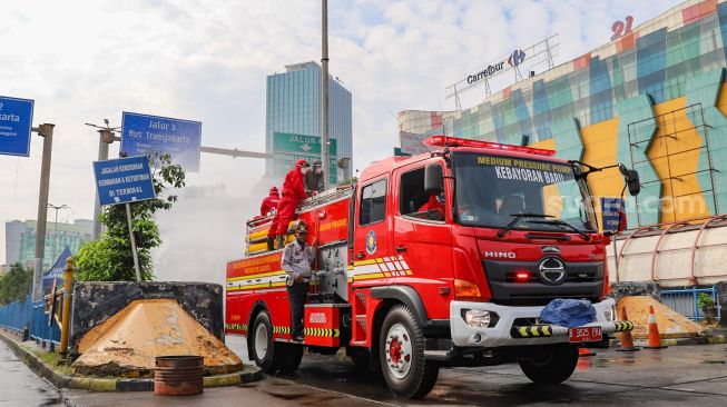 Petugas melakukan penyemprotan disinfektan di area Terminal Blok M, Jakarta Selatan, Selasa (23/6).  [Suara.com/Alfian Winanto]