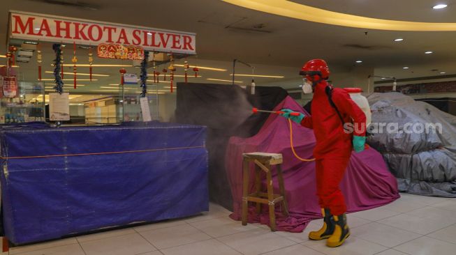 Petugas menyemprotkan disinfektan ke gerai toko yang tutup di Blok M Square, Jakarta Selatan, Selasa (23/6). [Suara.com/Alfian Winanto]