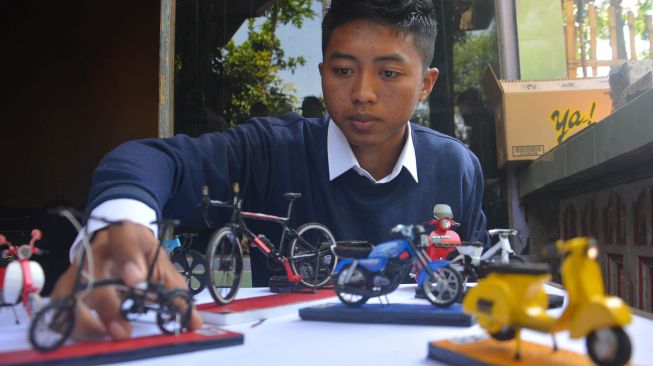 Perajin Aji Wahyu Santoso, menunjukkan berbagai miniatur sepeda berbahan limbah kartu perdana seluler di Desa Ngogri, Kecamatan Megaluh, Kabupaten Jombang, Jawa Timur, Selasa (23/6/2020). [ANTARA FOTO/Syaiful Arif]