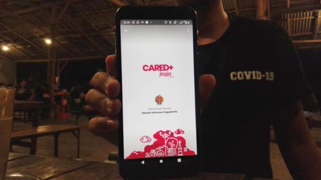 Salah seorang pengguna menunjukkan aplikasi Cared+ Jogja yang telah diunduh di handphone miliknya. - (SuaraJogja.id/Muhammad Ilham Baktora)
