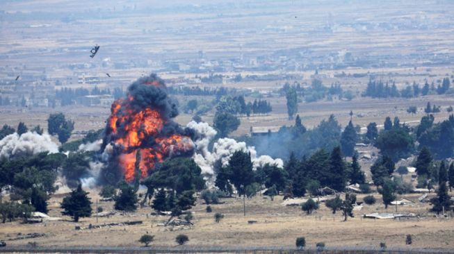 Ledakan terlihat di Quneitra, sisi Suriah pada perbatasan Suriah-Israel dilihat dari wilayah pendudukan Israel, Golan Heights, Israel, Minggu (22/7/2018). (Antara/REUTERS/Ronen Zvulun) 