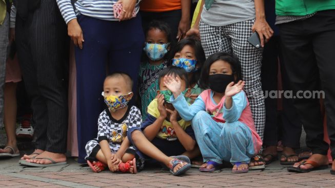 Anak - anak ikut melihat rekonstruksi rekonstruksi kelompok John Kei di Perumahan Green Lake City, Kota Tangerang, Banten, Rabu (24/6). [Suara.com/Alfian Winanto]
