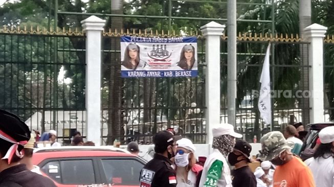 Poster bergambar Habib Bahar dibentangkan di depn pagar Gedung DPR, Senayan, Jakarta. (Suara.com/Yosea Arga)