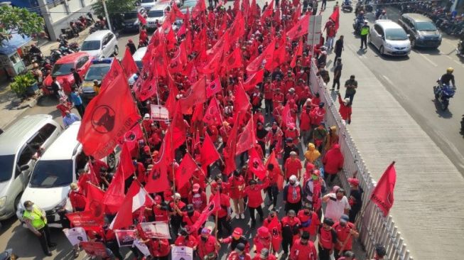 Massa PDIP Jakarta Timur melakukan aksi jalan kaki di Jalan Matraman Raya menuju Mapolrestro Jakarta Timur untuk menuntut pelaku pembakaran bendera partai ditangkap dan diadili sesuai hukum, Kamis (25/6/2020). (ANTARA/Andi Firdaus).