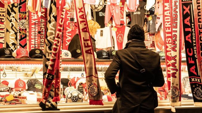 Penjualan pernak-pernik atau merchandise klub kontestan Liga Belanda, Ajax Amsterdam, di kota Amsterdam, Belanda. [Pepijn van Bakel / Shutterstock]