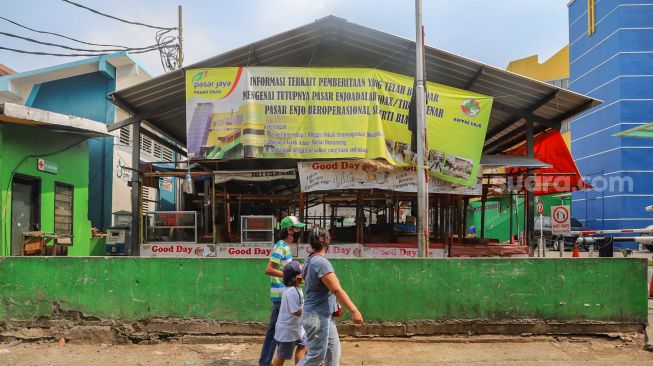 Warga melintas di area luar Pasar Enjo, Jakarta Timur, Jumat (26/6). [Suara.com/Alfian Winanto]