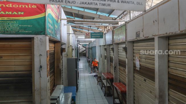 Pedagang duduk didepan tokonya yang tutup di Pasar Enjo, Jakarta Timur, Jumat (26/6). [Suara.com/Alfian Winanto]