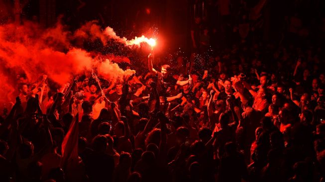 Suporter merayakan keberhasilan Liverpool menjadi juara Liga Inggris 2019/2020 di luar Anfield di Liverpool, Inggris, 25 Juni 2020.  [Oli SCARFF / AFP]