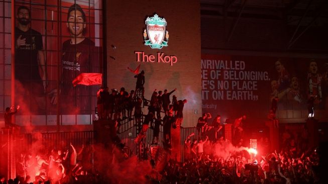 Di tengah pandemi COVID-19, para pendukung Liverpool melakukan perayaan di luar Stadion Anfield, Liverpool, Jumat (26/6/2020) dini hari WIB. Liverpool dipastikan menjuarai Liga Inggris 2019/2020 usai kekalahan 1-2 Manchester City di markas Chelsea. [OLI SCARFF / AFP]