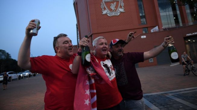 Di tengah pandemi COVID-19, para pendukung Liverpool melakukan perayaan di luar Stadion Anfield, Liverpool, Jumat (26/6/2020). Liverpool dipastikan menjuarai Liga Inggris 2019/2020 usai kekalahan 1-2 Manchester City di markas Chelsea. [Oli Scarff / AFP]