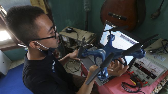 Pelajar Madrasah Aliyah Negeri 2 Kota Kediri, Muhammad Azhar Syahruddin melakukan pemrograman pesawat nirawak (drone) buatannya di Desa Bendo, Kediri, Jawa Timur, Sabtu (27/6). [ANTARA FOTO/Prasetia Fauzani]