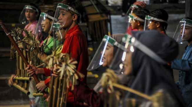 Pemain angklung menggunakan pelindung wajah saat menghibur wisatawan di Saung Angklung Udjo, Bandung, Jawa Barat, Sabtu (27/6). [ANTARA FOTO/Raisan Al Farisi]