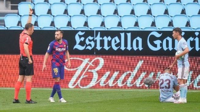 Pemain Barcelona Jordi Alba menerima kartu kuning saat menghadapi Celta Vigo di Balaidos, Sabtu (27/6/2020). [AFP]